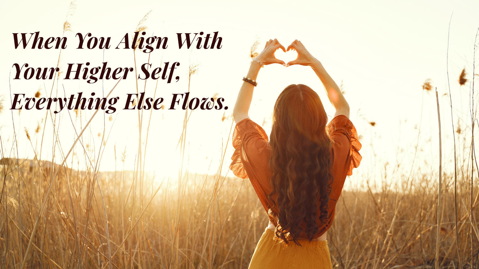 Woman standing in golden field with arms raised symbolizing alignment with higher self